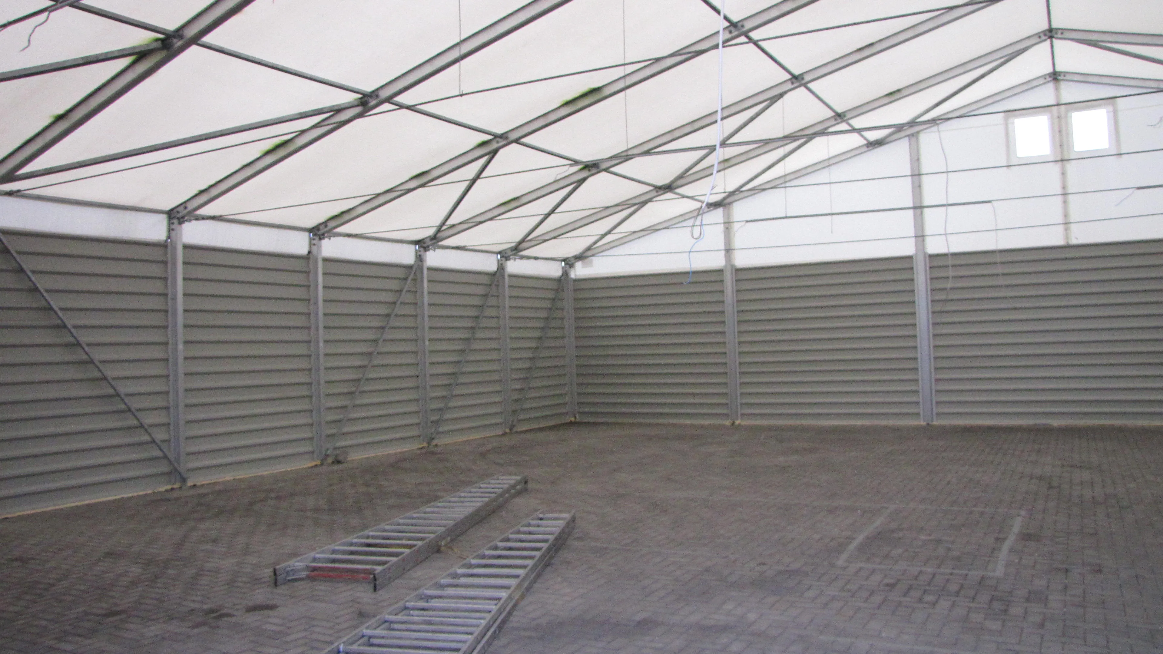 Leerer Innenraum eines Lagerzelts mit Aluminium-Rahmentragwerk und grauen Trapezblech-Seitenwänden